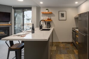 A modern kitchen with a marble countertop, a built-in stove, a stainless steel refrigerator, and a coffee maker. - Big Mauna at the Marquise (Whistler)