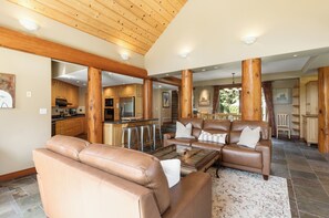 A spacious living area with a leather sofa, a glass coffee table, and a wooden ceiling.