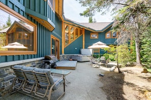 A house with a patio area featuring outdoor furniture, a grill, and a stone wall.
