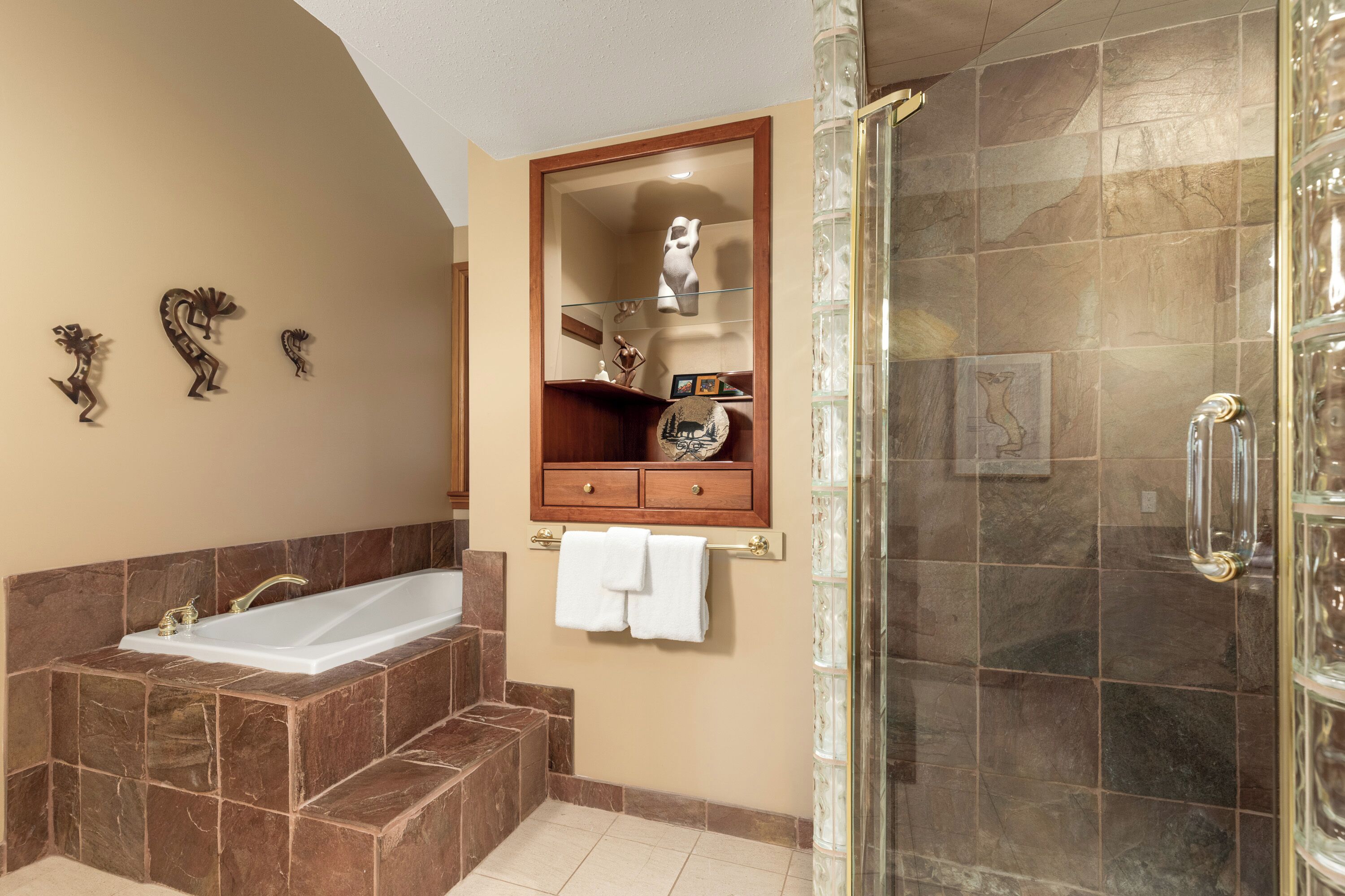 A bathroom with a bathtub, a glass shower enclosure, and a vanity with a mirror.