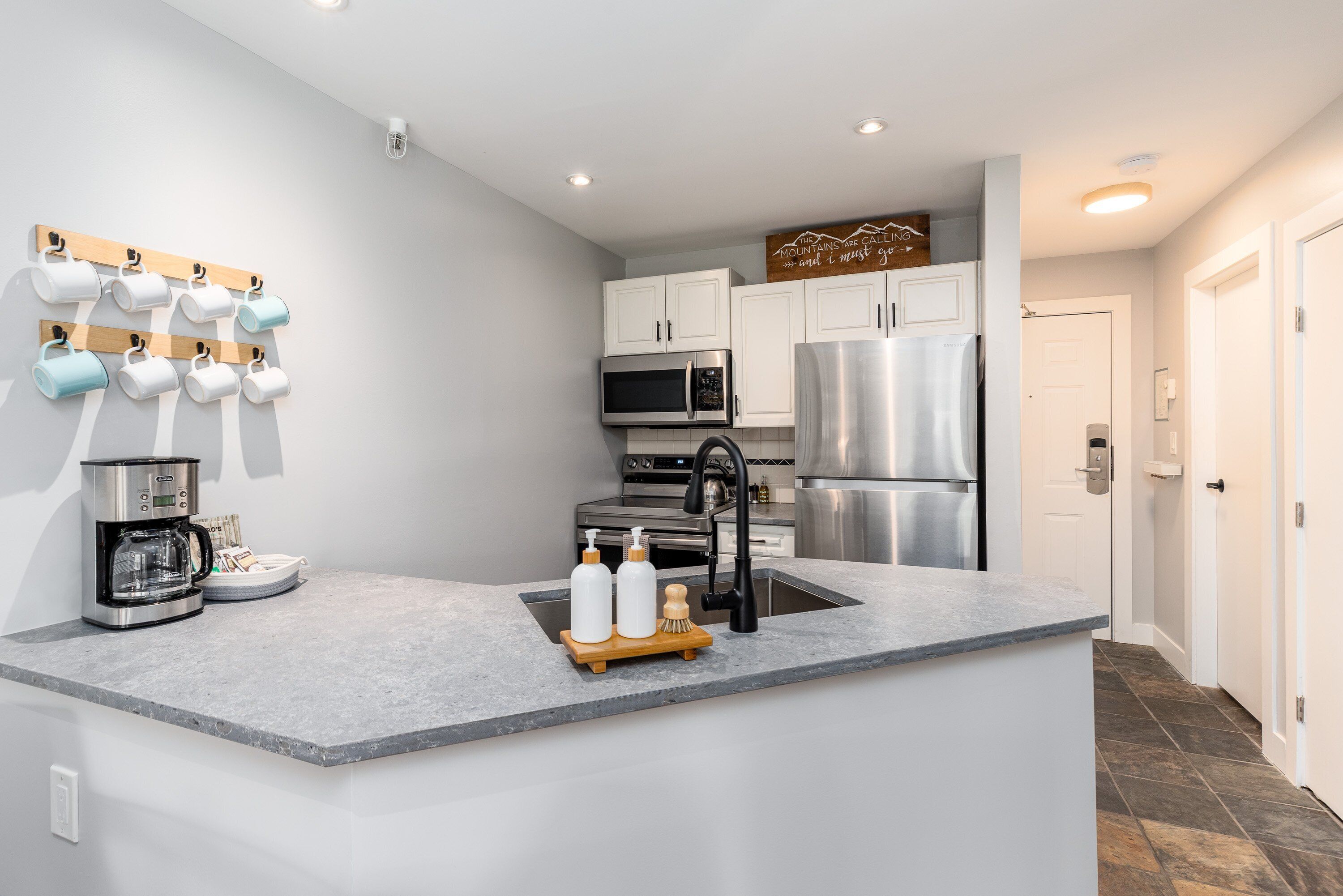 A modern kitchen with a central island, stainless steel appliances, and a coffee maker.