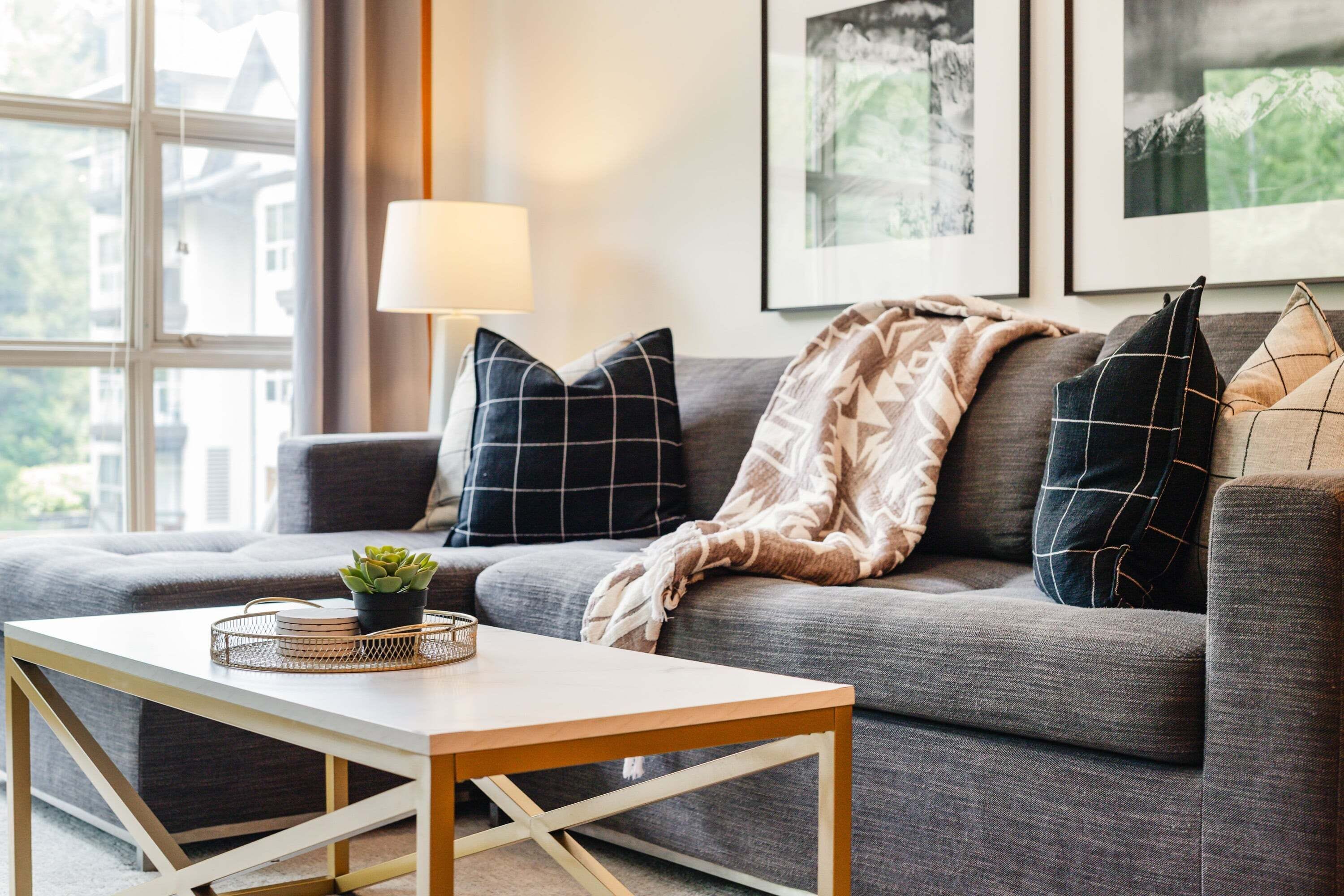 Ein modernes Wohnzimmer mit einem grauen Sofa, einem weißen Couchtisch und einer Stehlampe.