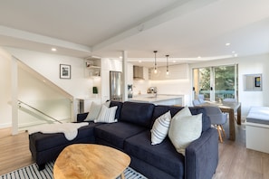 A modern living room with a dark blue sofa, a wooden coffee table, and a staircase leading to an upper level. - Sapphire Retreat at Snowbird (Whistler)