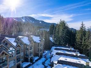 A multi-story building with a snow-covered roof, surrounded by trees and mountains. - Sapphire Retreat at Snowbird (Whistler)