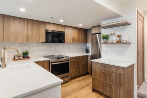A modern kitchen with wooden cabinets, stainless steel appliances, and a white countertop. - Summit View at The Lagoons (Whistler)