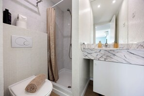 A bathroom with a toilet, shower, and a marble countertop with a sink. - Blue Marine by Lagos Apartment at Lagos Marina (Lagos)