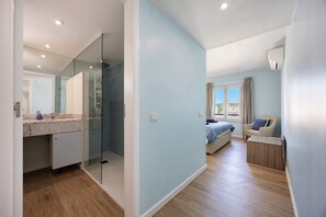 A modern bedroom with a bed, a window, and a bathroom with a glass shower. - Blue Marine by Lagos Apartment at Lagos Marina (Lagos)
