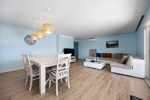 A modern living room with a dining area, a sofa, and a television.