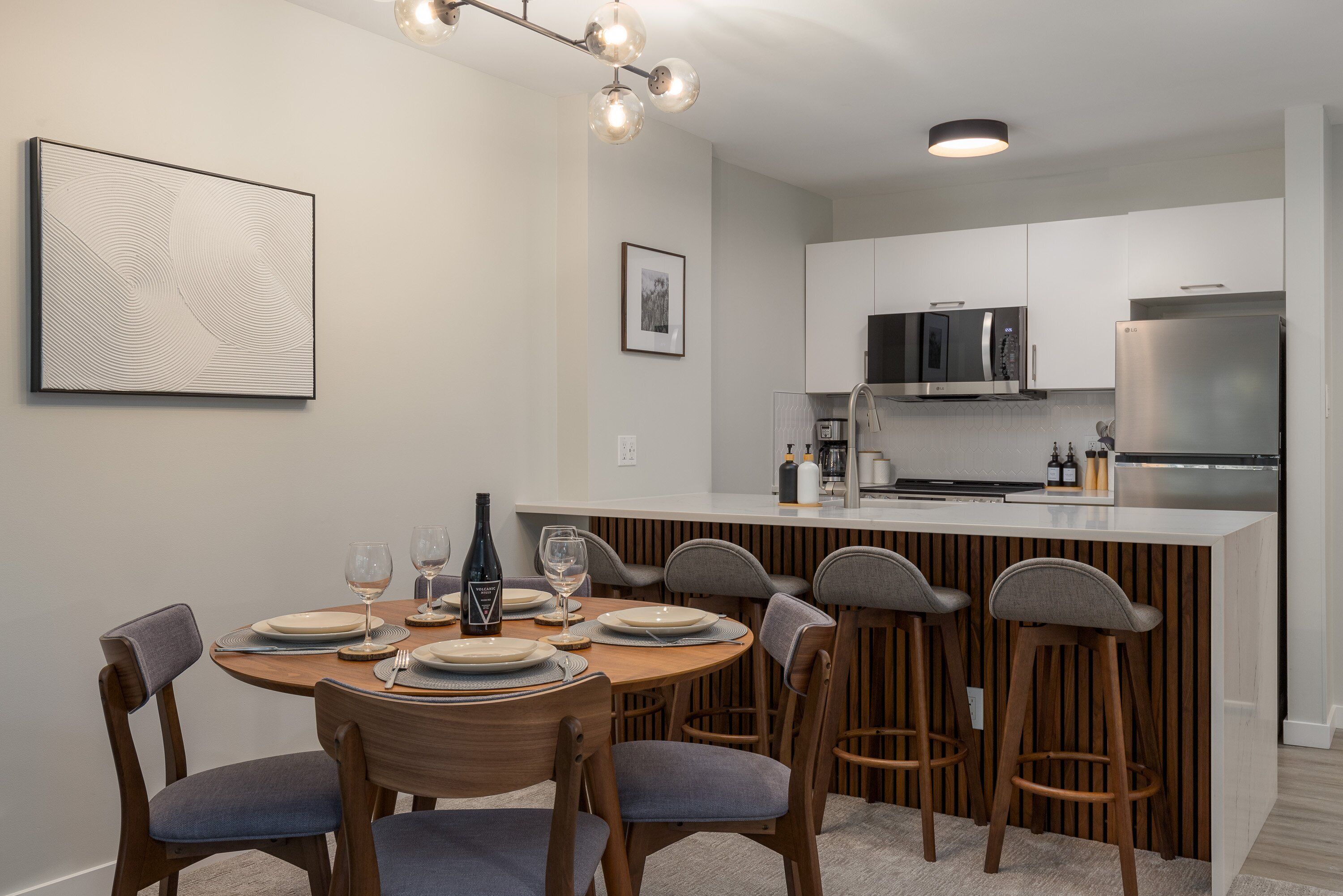 A modern kitchen with white cabinets, stainless steel appliances, and a central island with bar stools.