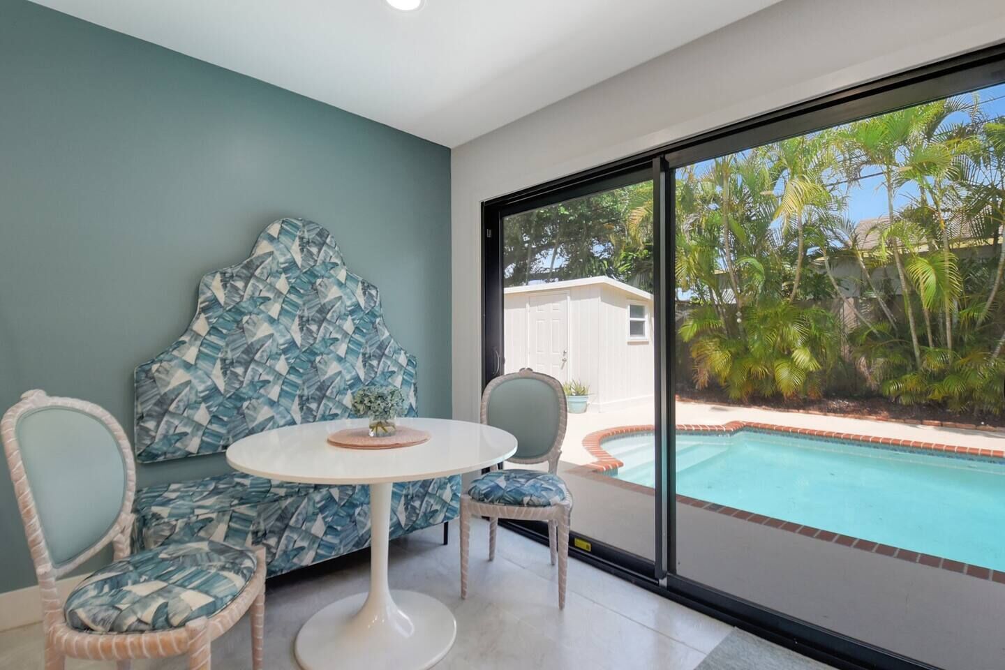 Une pièce dotée d’une grande fenêtre, d’une piscine et d’un espace salon avec une table et des chaises.