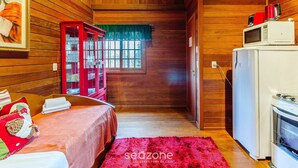 A cozy cabin interior with a bed, a red cabinet, a microwave, and a refrigerator. - Santa's Cabin in Gramado Rar065 (Gramado)