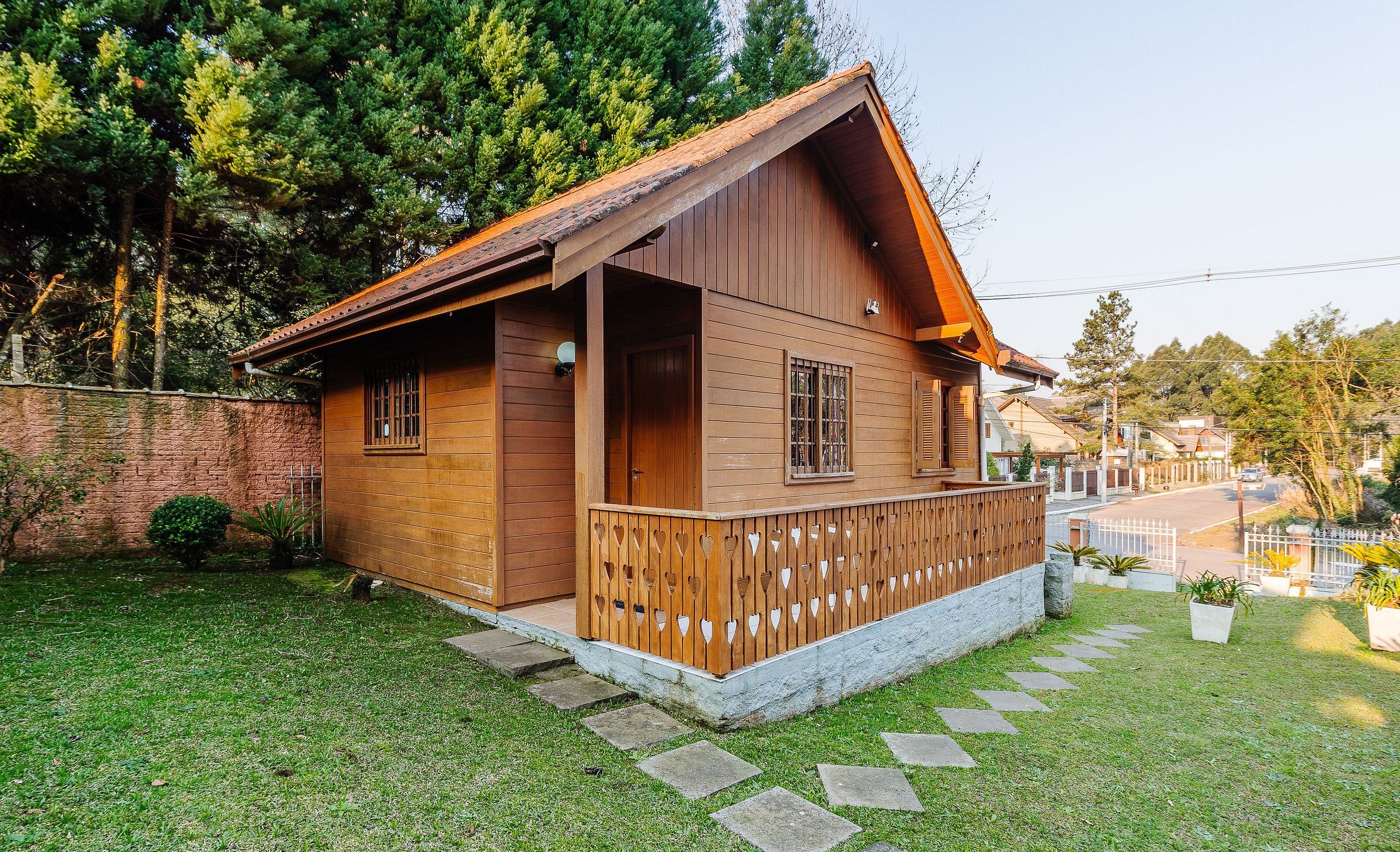 A wooden cabin with a porch, a small garden, and a stone pathway leading to the entrance.