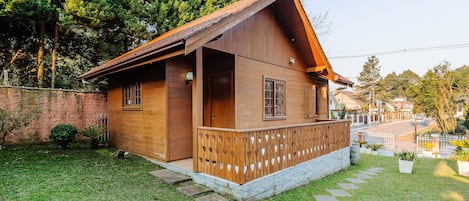 A wooden cabin with a porch, a small garden, and a stone pathway leading to the entrance.