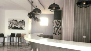 A modern reception area with a curved counter, hexagonal tile flooring, and pendant lighting.