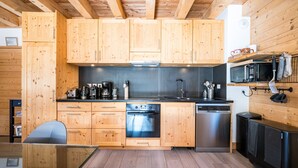 A modern kitchen with wooden cabinets, stainless steel appliances, and a glass dining table. - Charming Chalet for Ski & Mountain Stay (Valloire)