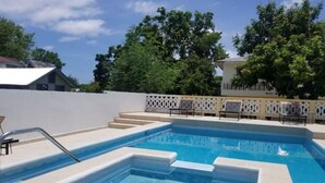 A rectangular swimming pool with steps leading into it, surrounded by a white fence and a row of sun loungers. - A Rooftop View, Comfort & Event-Ready Spaces - #01 &02 (Negril)