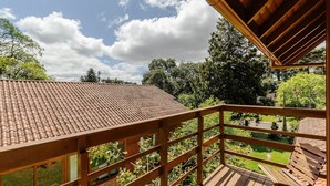 A wooden balcony with a tiled roof overlooking a garden. - House With Barbecue in Gramado Rje0980 (Gramado)