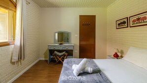 A bedroom with a bed, a wooden desk, a chair, a mirror, a door, and a nightstand with a lamp. - House With Barbecue in Gramado Rje0980 (Gramado)