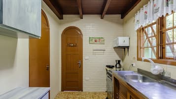 A compact kitchen with a wooden door, a microwave, a coffee maker, and a sink.
