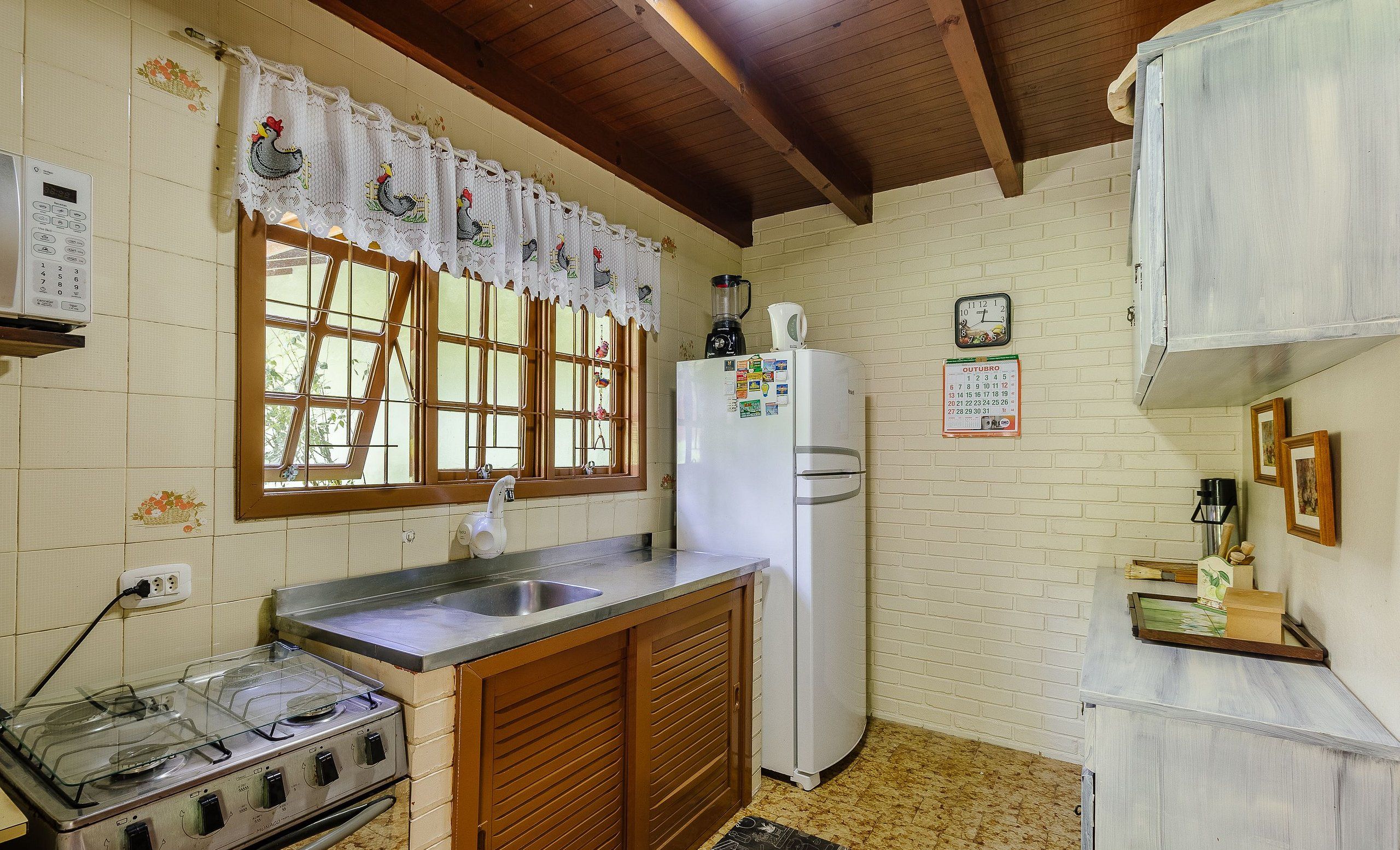 A kitchen with a stove, sink, refrigerator, and wooden cabinets.