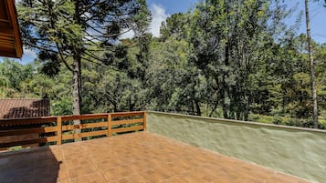 A wooden deck with a green wall and a view of dense trees.