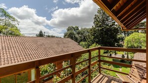 A wooden balcony with a tiled roof overlooking a garden. - House With Barbecue in Gramado Rje0980 (Gramado)