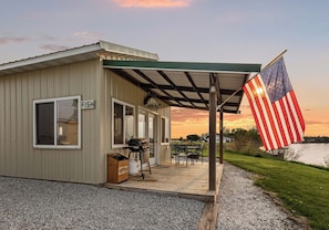 A waterfront property with a covered patio, outdoor seating, and an American flag.