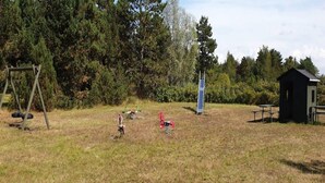An outdoor area with a swing set, a small shed, and picnic tables. - 4 Star Holiday Home in Rodby (Rodby)