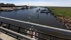 A canal with boats docked on the left, a grassy bank on the right, and a bridge in the foreground. - 4 Star Holiday Home in Rodby (Rodby)