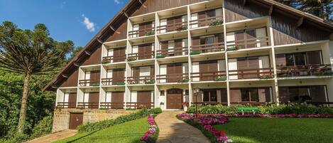 A multi-story hotel with balconies, a stone pathway, and a well-maintained garden.