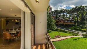 A balcony with a view of a well-maintained garden and a road. - Apartment With 2 Bedrooms and Lake View Rla0201 (Gramado)