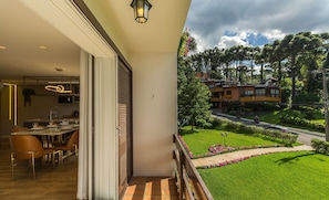 A balcony with a view of a well-maintained garden and a road. - Apartment With 2 Bedrooms and Lake View Rla0201 (Gramado)