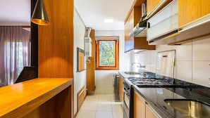 A modern kitchen with wooden cabinets, a black countertop, and a window providing natural light.