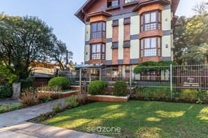 A multi-story building with a brick facade, large windows, and a gated entrance. - Apt w/ BBQ 1km From Gramado Center Sds104 (Gramado)