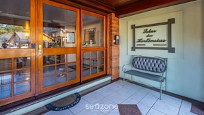 A wooden entrance with glass doors, a bench, and a wall sign reading "Solar da Hortência".