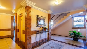 A hotel lobby with a brick accent wall, a mirror, a staircase, and a potted plant.
