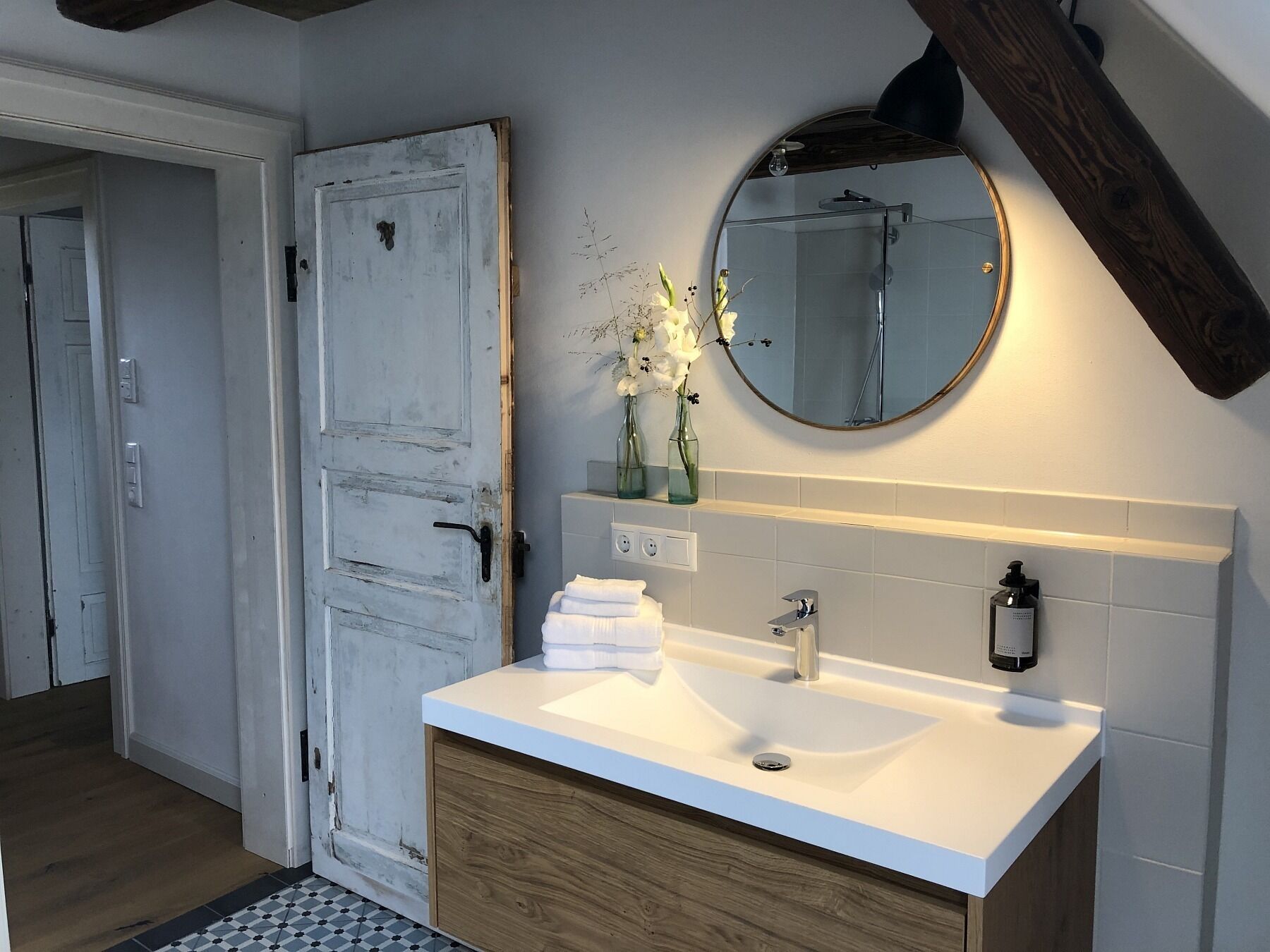A bathroom with a white sink, wooden cabinet, and a mirror above the sink.
