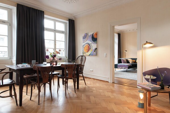 A dining area with a wooden table and chairs, a vase with flowers, and a painting on the wall. - Palais Wunderlich (Lahr)
