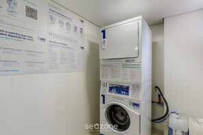 Una lavadora de carga frontal con panel de control, un código QR, un depósito de agua y una manguera.