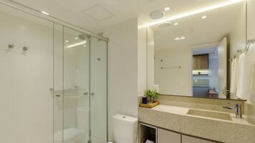 A modern bathroom with a glass-enclosed shower, a large mirror, and a granite countertop.