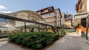 A modern building with a glass facade and a covered outdoor seating area. - Beautiful Apart With 2 Bedrooms in Gramado Vdb0201 (Gramado)