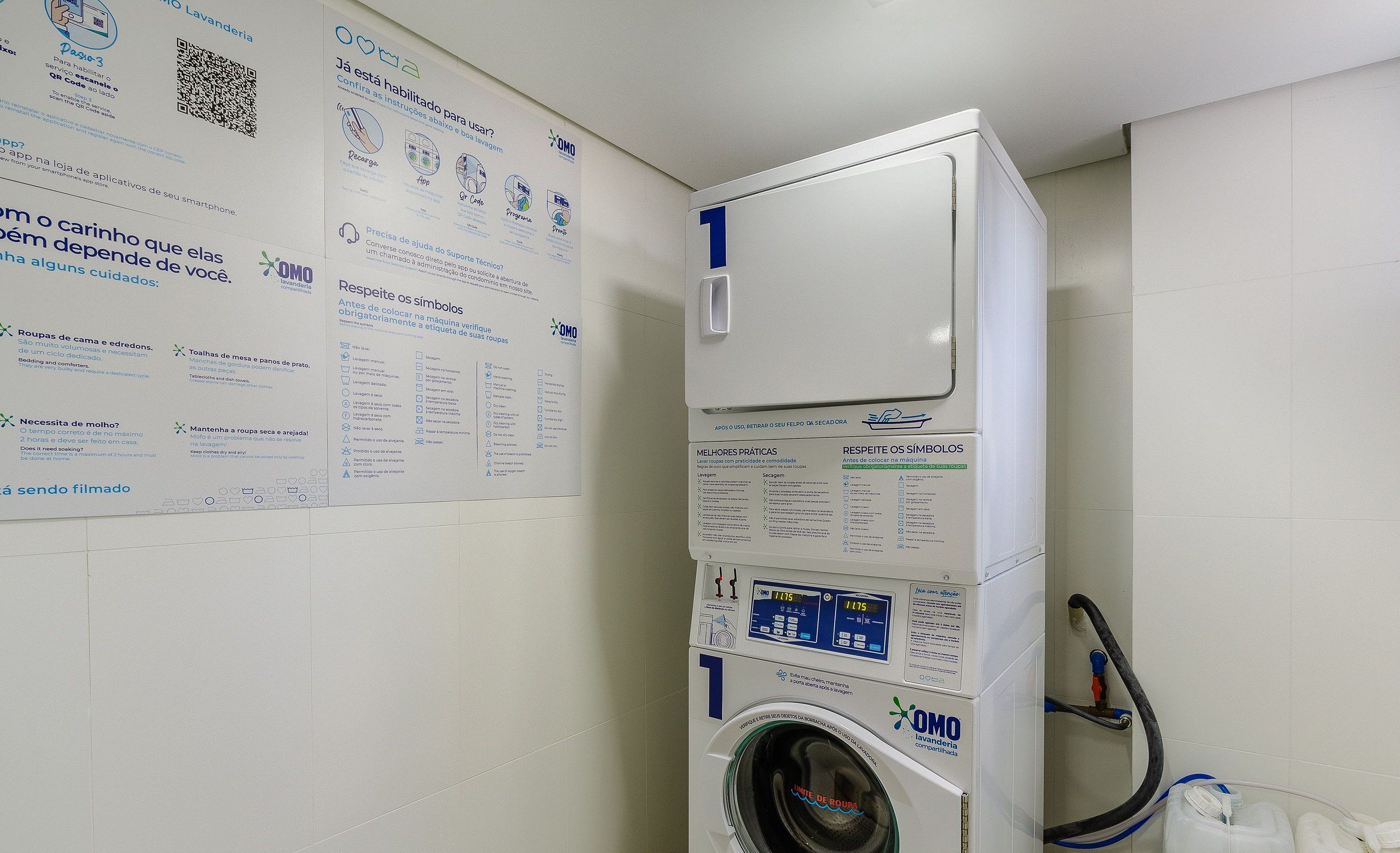 En vaskemaskine med frontåbning, kontrolpanel og QR-kode, samt en vandtank og en slange.