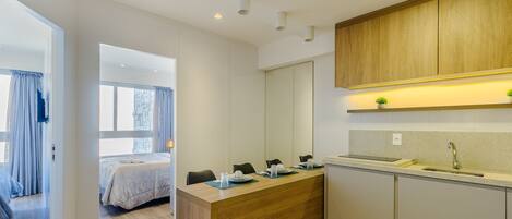 Una cocina moderna con armarios de madera, una encimera y un lavamanos. Hay un comedor con una mesa y sillas.