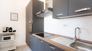 A modern kitchen with grey cabinets, a stainless steel sink, and a built-in oven. - Rental in Rome Constance Terrace Apartment (Rome)