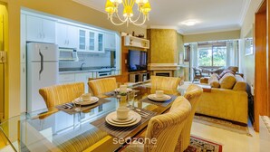 Una sala de estar moderna con una mesa de comedor de vidrio, sillas amarillas, un sofá y un televisor.