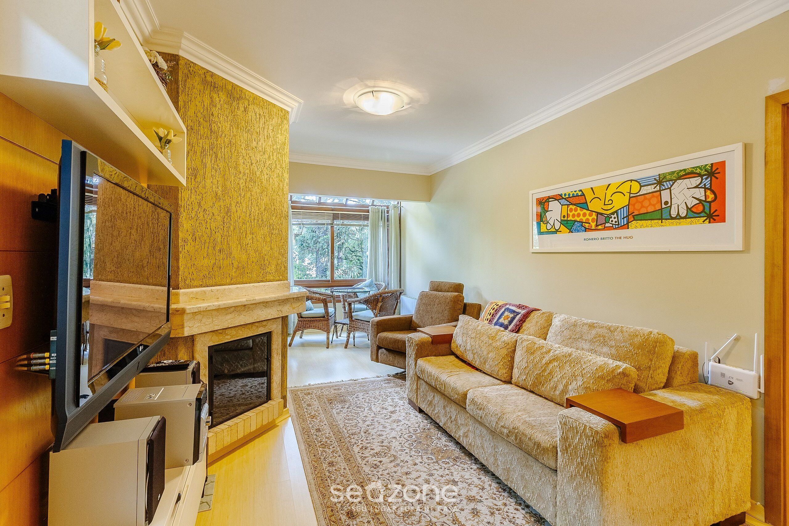 A living room with a fireplace, sofa, and a painting on the wall.