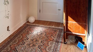 Una habitación con un tapete estampado, una puerta blanca y un armario de madera.