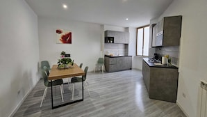 Una cocina moderna con armarios grises, una isla central y un comedor con una mesa y sillas de madera.