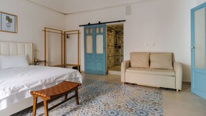 A bedroom with a bed, a bench, a sofa, and a door leading to a bathroom. - Dolce Vita Central Apartment by Wonderful Italy (Catania)