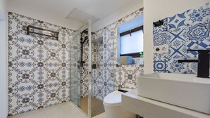 A bathroom with patterned walls, a glass shower enclosure, and a white sink. - Dolce Vita Central Apartment by Wonderful Italy (Catania)